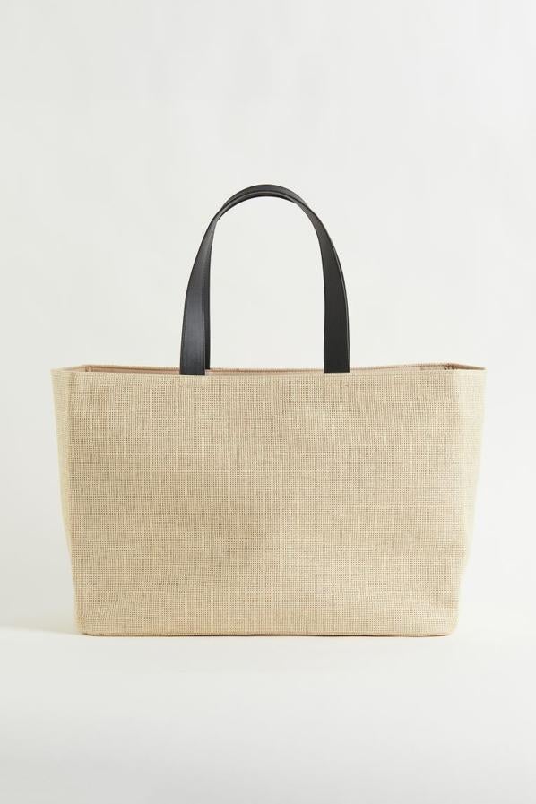 Para ir a la playa o a la piscina H&m ha incluido en su última colección este bolso en beige claro, con asas de piel sintética a contraste en color negro, cierre magnético en la parte superior y compartimento interior pequeño. Podemos comprarlo por 19,99 euros. 