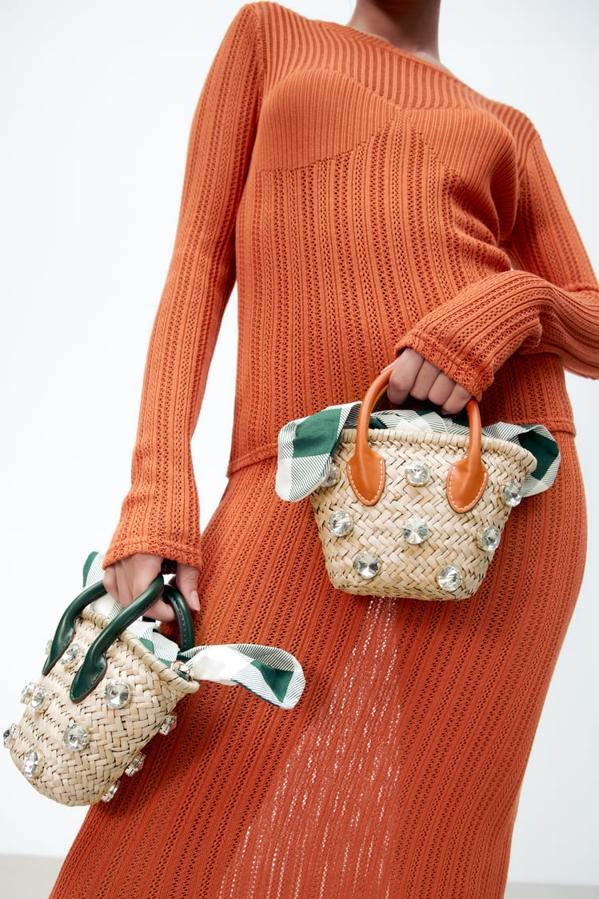 Formato mini cesta para este bolso con cuerpo trenzado con detalle de brillos que podemos encontrar en Zara con las asas en dos tonos diferentes, negro o naranja. Con cierre mediante nudo, tiene un precio de 25,95 euros. 