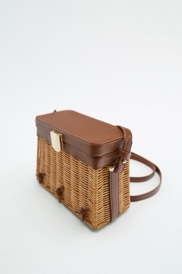 Cuerpo de ratán y asas y solapa en polipiel para este bolso en formato caja de Zara que tiene el interior forrado y viene con cierre metálico. Cuesta 29,95 euros. 