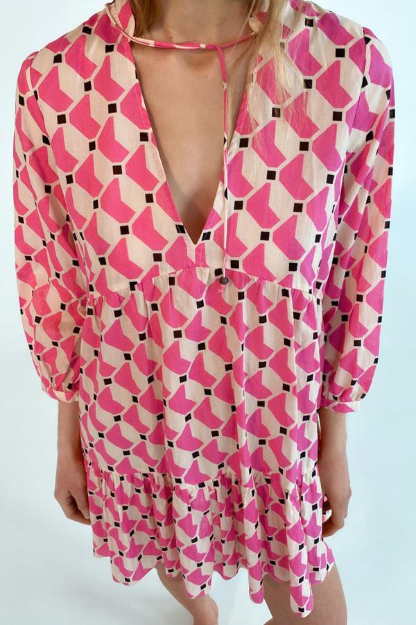 Estampado geométrico en tonos rosas y blancos para este vestido corto de Zara con cuello redondo y escote de pico que tiene mangas tres cuartos y bajo acabado en volante. Tiene un precio de 29,95 euros. 