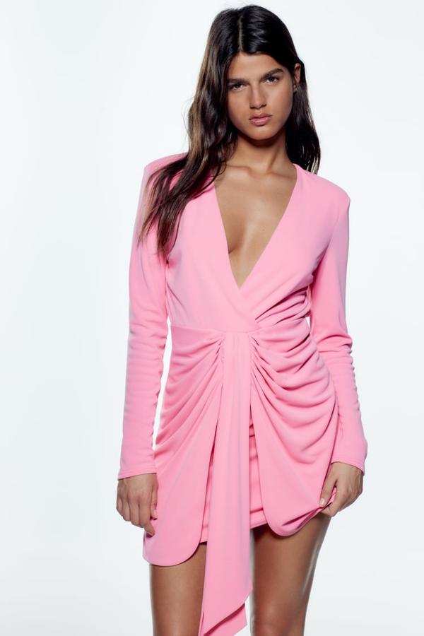 Con detalle de nudo y tejido drapeado en delantero, este vestido rosa de diseño corto y escote de pico pronunciado es de Zara, viene con mangas largas con hombreras y podemos comprarlo por 29,95 euros. 