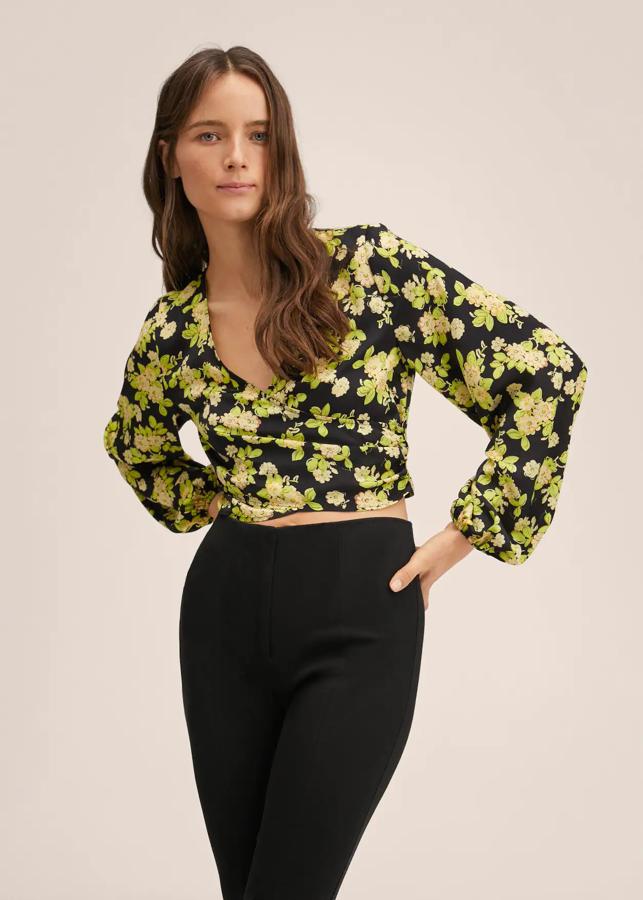Diseño evasé cropped para esta blusa negra con estampado floral en lima y crema que está confeccionada en tejido satinado ligero, tiene el cuello cruzado y las mangas largas con puños elásticos. Está rebajada y de 29,99 euros ha pasado a costar 19,99 euros. 
