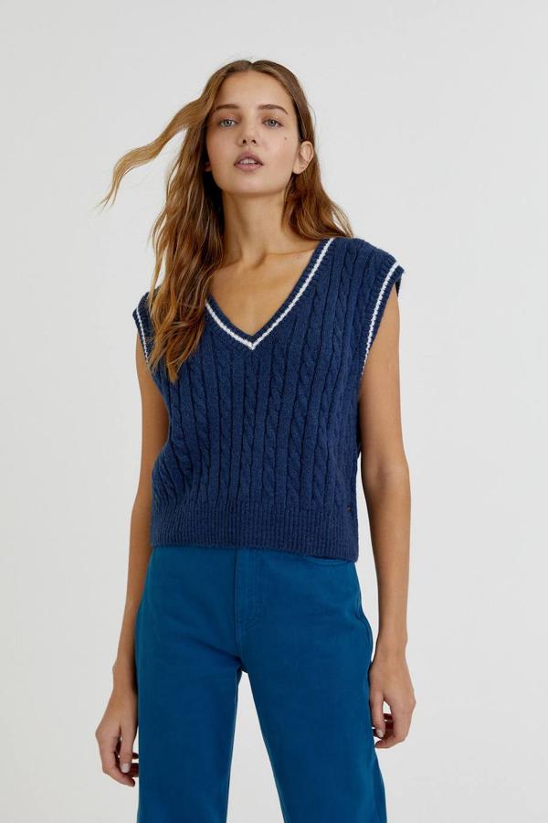 Chaleco de punto con diseño de ochos, tipo cricket con líneas en cuello y mangas, escote de pico, manga sisa y terminaciones en rib, a 19,99 euros. Está disponible en 3 colores, azul, gris y negro, en las tallas S, M y L, en la nueva colección de Pull&Bear.