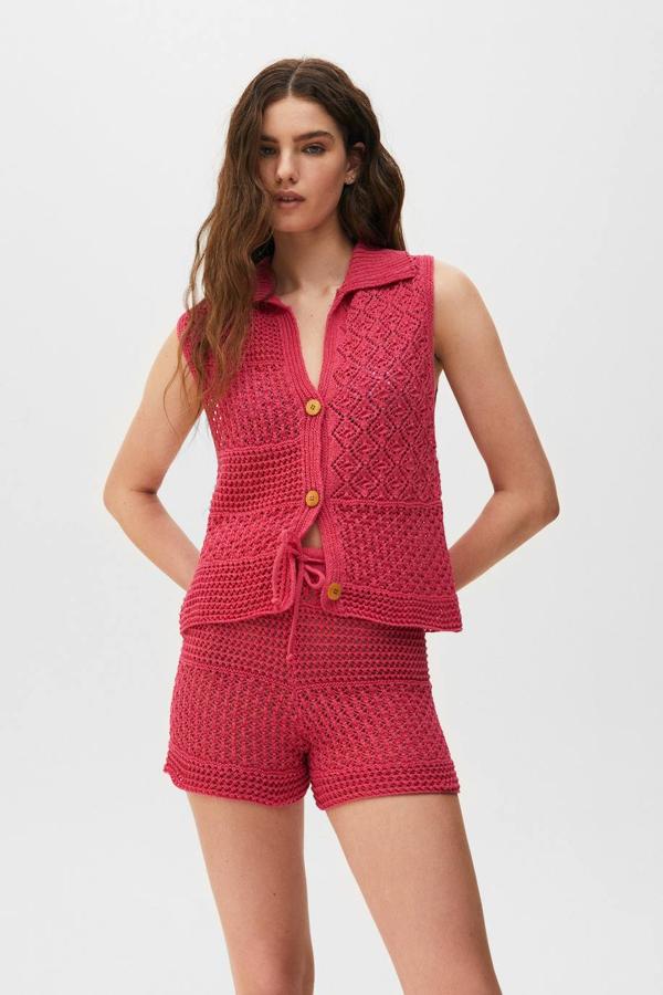 Chaleco de crochet con diseño abierto, cierre de botones, manga sisa y cuello tipo polo, en tono rosa fucsia, por 22,99 euros. Encuéntralo en Pull&Bear, de la XS a la L.