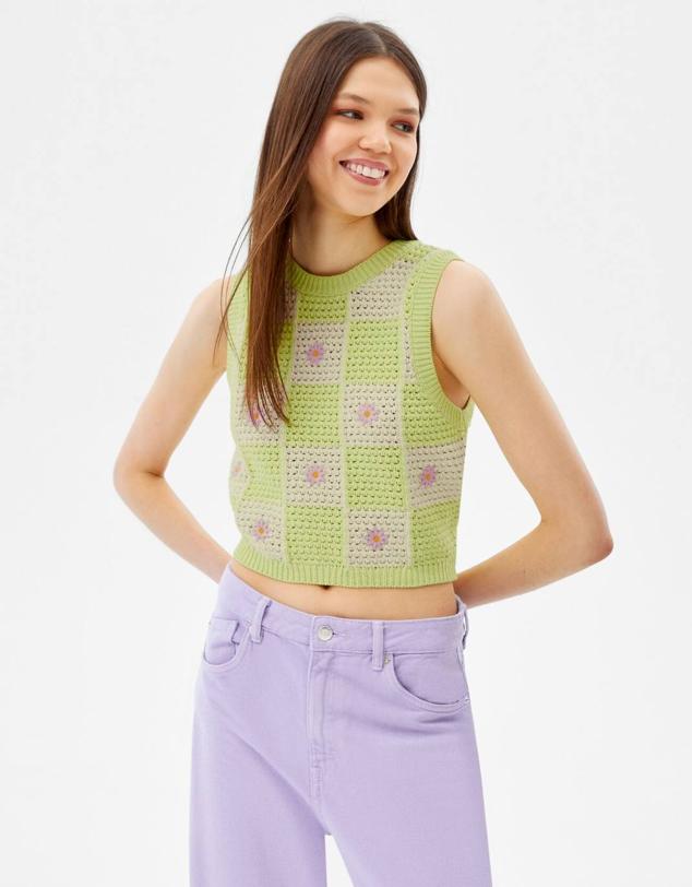 Chaleco de punto a cuadros con detalle de bordados de flores, corte recto, cuello redondo, manga sisa y acabados en rib, en verde lima, crudo y lila, por 19,99 euros. Está disponible de la talla XS a la XL en Bershka.