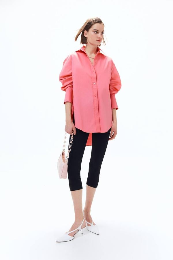 Camisa confeccionada en tejido de popelín con diseño oversize, bajo asimétrico, manga larga terminada en puños anchos y cierre de botones, color rosa, de Sfera. Su precio es de 29,99 euros.