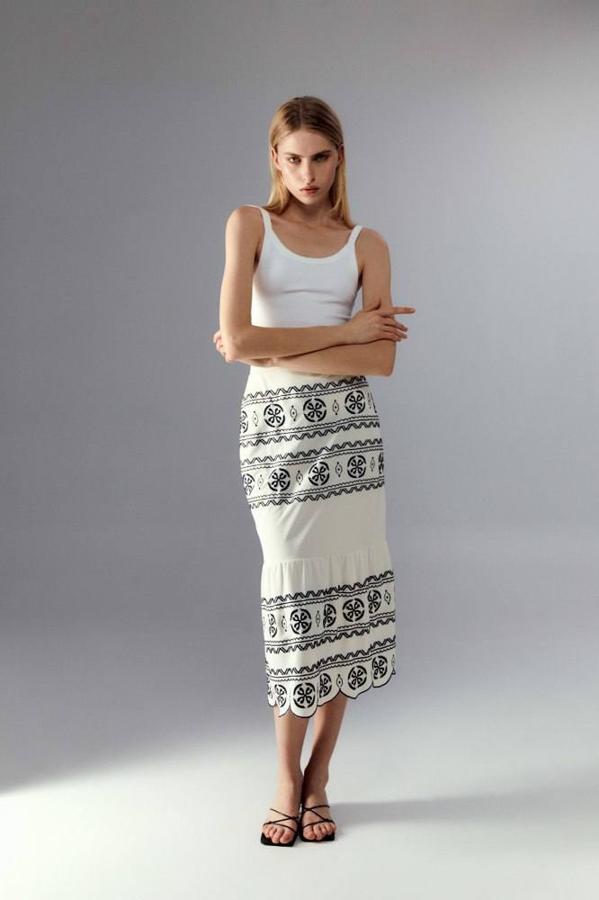 Falda midi con tiro alto, silueta acomodada a la figura, bajo de volate fruncido con acabado festoneado y detalle de bordados, en arena y negro. Puedes comprarla a solo 21,99 euros y entre las tallas S y XL.