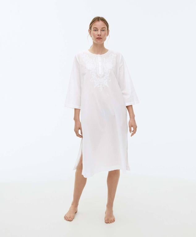 Vestido túnica midi en tejido 100% algodón, con fit oversize, manga larga amplia, cuello redondo con cierre frontal de botones, aberturas a los laterales del bajo y detalle bordado en el pecho, color blanco, de Oysho. Tiene un coste de 35,99 euros.