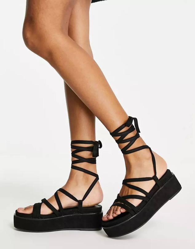 Sandalia de tiras finas anudadas y plataforma plana en color negro, de Asos. Está disponible por 31,99 euros.