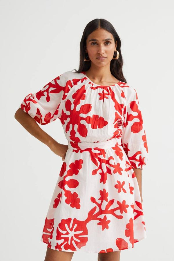 Vestido corto de algodón con cuello redondo, mangas tres cuartos con volumen, abertura en la espalda, corte holgado y cinturón de lazada a conjunto, decorado con estampado en rojo y blanco. Tiene un coste de 34,99 euros.