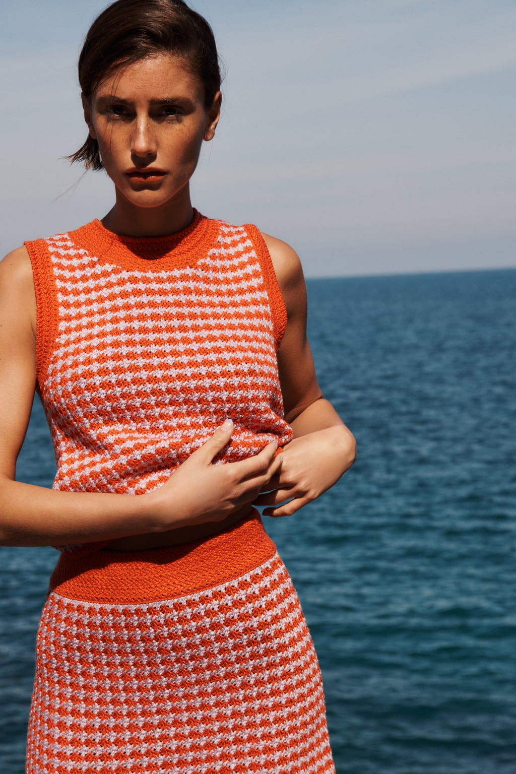 Los conjuntos de punto, de top y mini falda, son la opción perfecta para conseguir un total look con sabor veraniego. Top de punto en color naranja de Zara (22,99 euros)