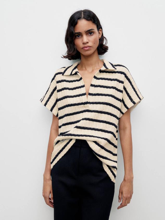 Polo confeccionado en tejido de algodón texturizado ligero con estampado a rayas horizontales, cuello solapa con escote de pico, manga corta y silueta relajada, color crudo y negro, de Massimo Dutti. Tiene un coste de 39,95 euros.