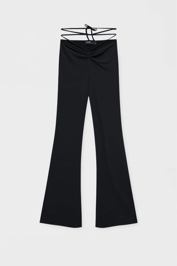 Pantalones flare o acampanados con tiras para estilizar la zona del vientre. Son de Pull&Bear y se convertirán en un básico de armario por su color negro. Precio: 17,99 €.