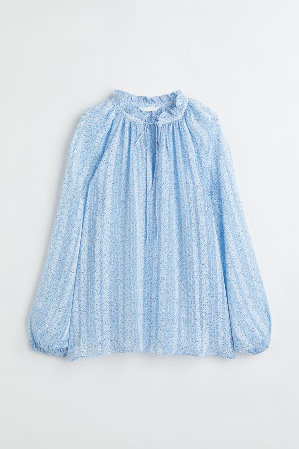 De estilo romántico y floral. Así es la blusa en tejido fluido con cuello de volante corto y abertura con lazada delante. Pertenece a la nueva colección de H&M y podrás comprarla en beige, celeste o blanca. Precio: 14,99 €.