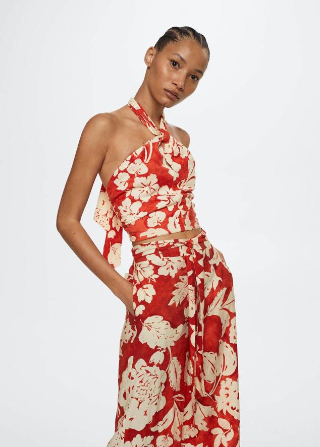 Top crop en tejido de lino con estampado floral tropical, cuello halter ajustable mediante lazada, abertura en el escote y espalda al aire, color naranja y crudo, de Mango. Tiene un precio de 25,95 euros.