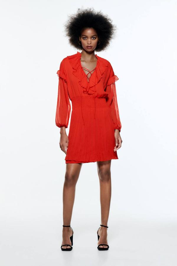 Vestido corto de tejido vaporoso semitransparente, con manga larga, falda con vuelo, cintura elástica, escote de pico con lazada y detalles de volantes, de Zara. Está disponible por 29,95 euros.