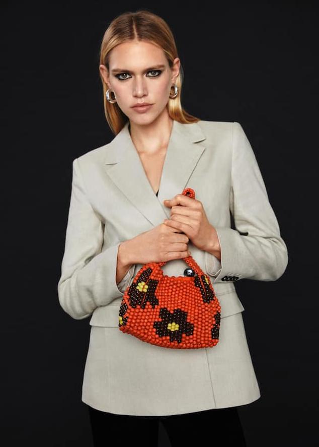 Un coqueto bolso que pondrá una nota de color a tus estilismos más osbrios. Bolso con flores de cuentas de Mango (39,99 euros)