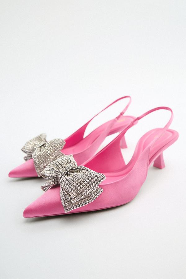 Zapato de tacón medio destalonado de tejido satinado en color rosa vibrante. Lo mejor es su lazo con brillos en la parte delantera Son de Zara. Precio: 79,95 €.