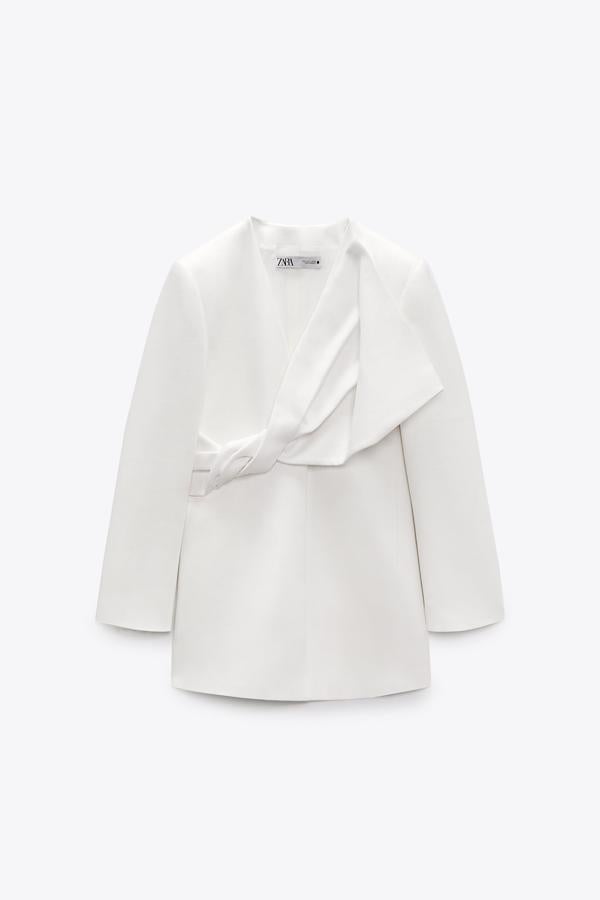 Este vestido tipo blazer de escote de pico en blanco, tiene el detalle más especial. Su nudo con pliegues en la parte delantera aporta volumen, creando una especie de maxi lazo. Es de Zara. Precio: 89,95 €.
