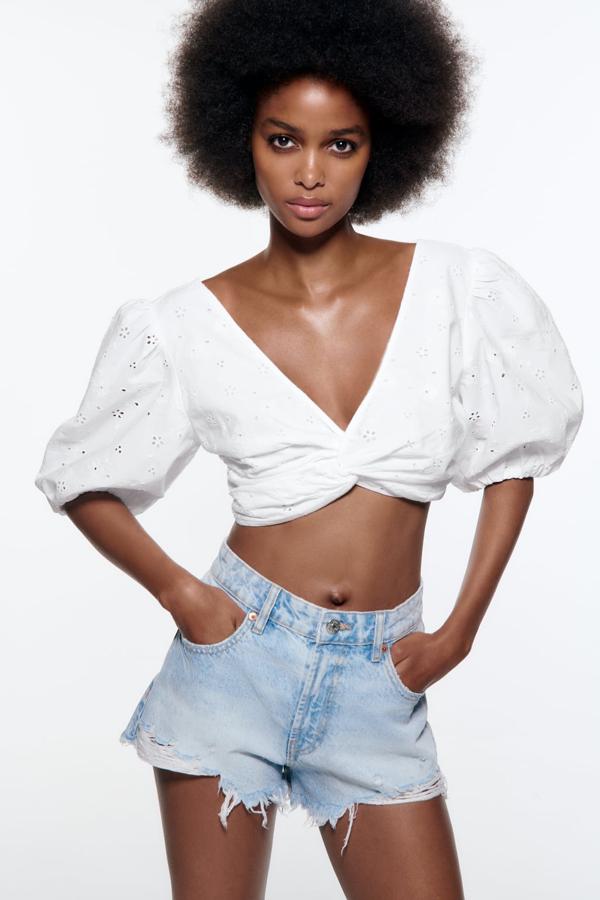 Una blusa blanca que no es como las demás. Con mangas abullonadas, calados y escote drapeado. Blusa de popelín de Zara (25,99 euros). 