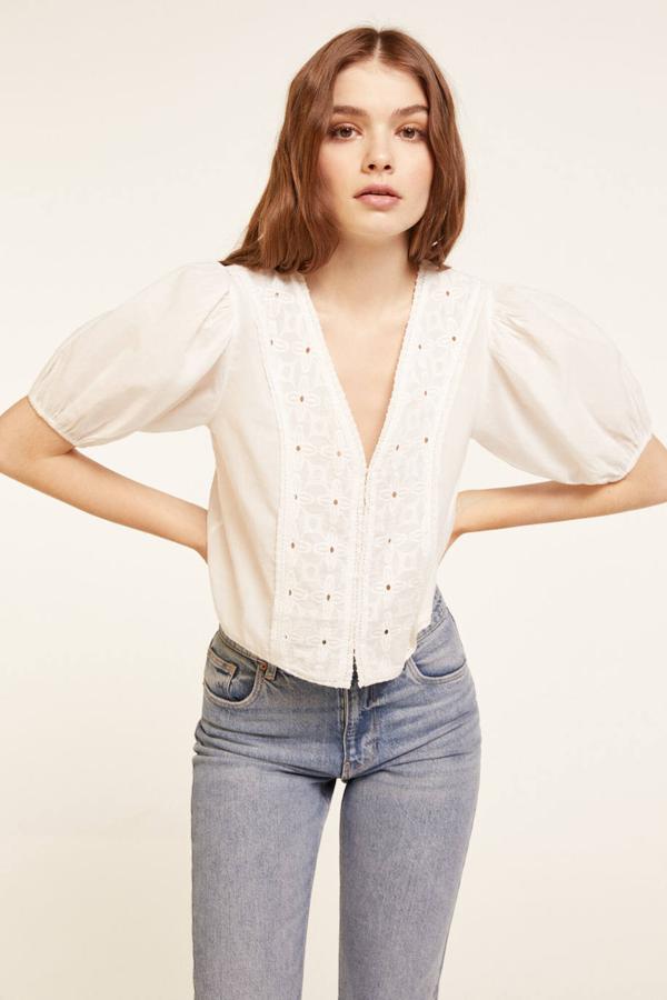 Blusa de tejido ligero con manga corta abullonada, escote de pico y detalle de cenefas con bordado suizo en el cuerpo, color blanco, de Springfield. La encontrarás rebajada a 19,99 euros.