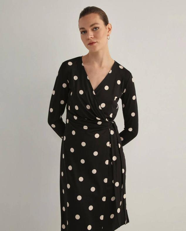 Vestido mini de tejido fluido con estampado de lunares en blanco y negro, de El Corte Inglés. Tiene cierre cruzado con detalle de lazada para anudar, manga larga y escote de pico. Está disponible en rebajas a 29,99 euros.