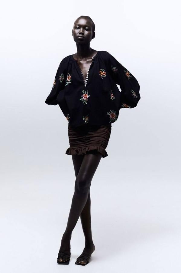 Blusa en tejido 100% algodón con manga larga abullonada, cuello caja con cierre de botones y bordados de flores a contraste, en color negro. Ahora cuesta 19,99 euros.