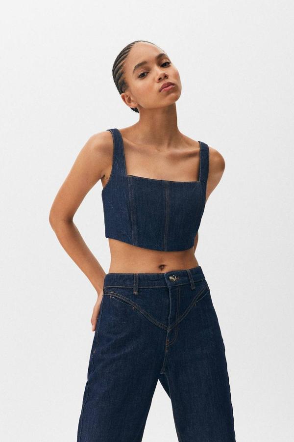 Top tipo corsé en tejido denim, con diseño crop, escote cuadrado, tirantes anchos y cierre de cremallera en la espalda, de Pull&Bear. Cómpralo rebajado a 12,99 euros.