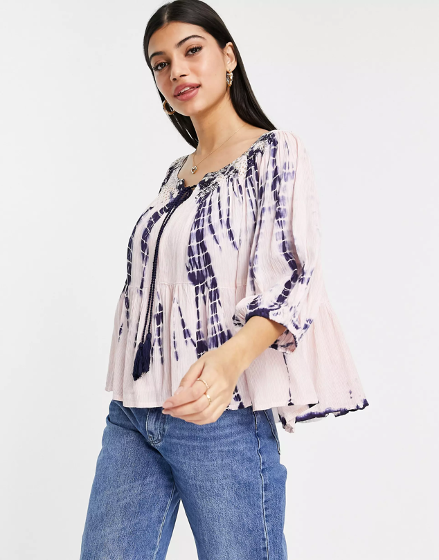 Destaca por sus bordados dorados y borlas en su cuello redondo. Además, su estampado tie dye rosa y morado es todo lo que necesitas esta temporada. Es de ASOS. Precio: 34,75 €.