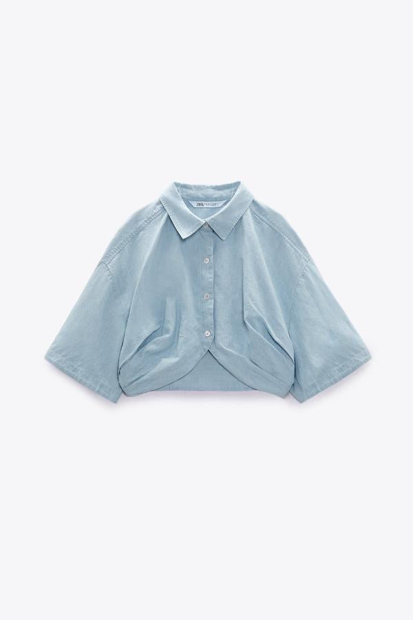 Camisa crop confeccionada en azul claro. Está diseñada con cuello solapa y manga corta. Es de Zara. Precio: 25,95 €. 