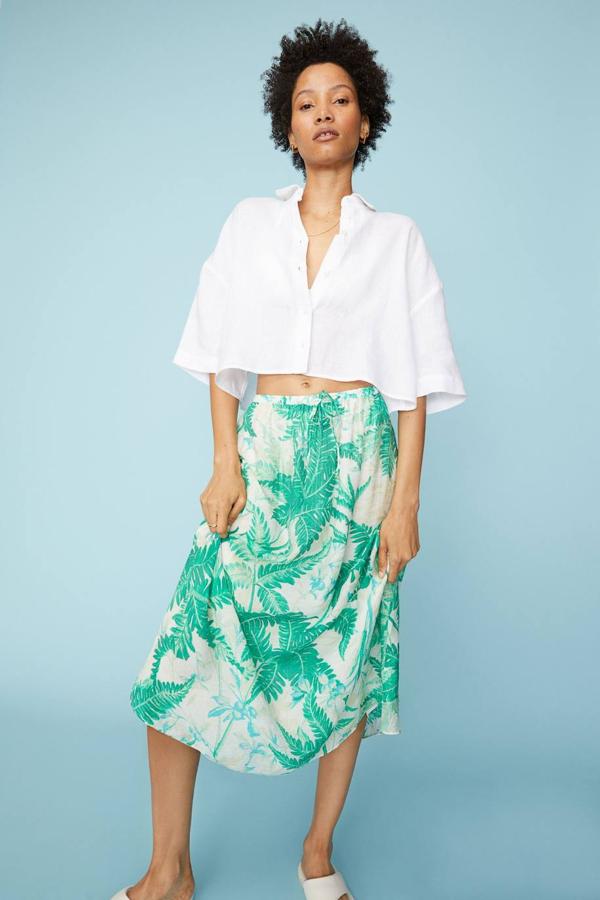 Falda midi confeccionada en tejido ligero, con vuelo, cintura elástica y estampado botánico en verde, de H&M. Está disponible por 29,99 euros.