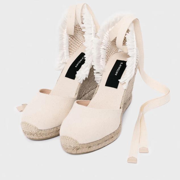 ¿No sabes qué tono elegir? El blanco roto es el color infalible en este tipo de calzado veraniego. Busca un diseño original con detalles desflecados. Alpargatas de cuña de esparto de Antonia´s (149 euros). 