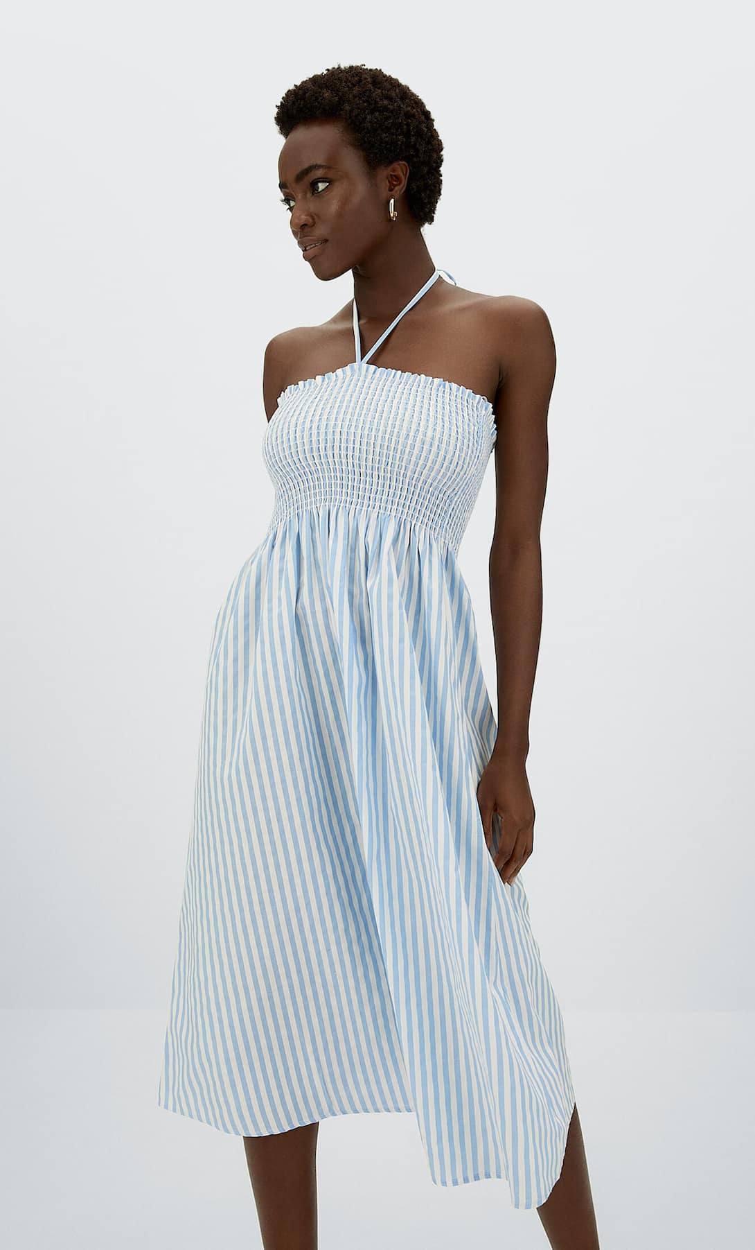 Vestido midi con fruncido de nido de abeja en el escote y tirantes finos con diseño halter. Cuenta con un estampado clásico de rayas verticales en azul y blanco. Precio:15,99 euros (antes, 22,99 euros).