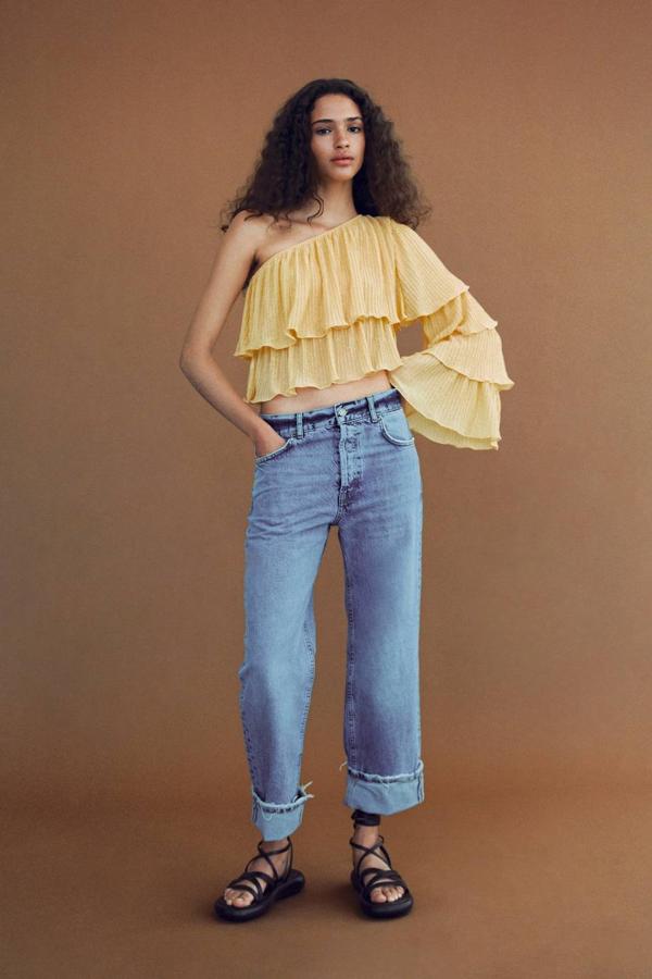 Top en tejido plisado con cuerpo de volantes y una manga larga, color amarillo claro. Puedes comprarlo por 22,95 euros.