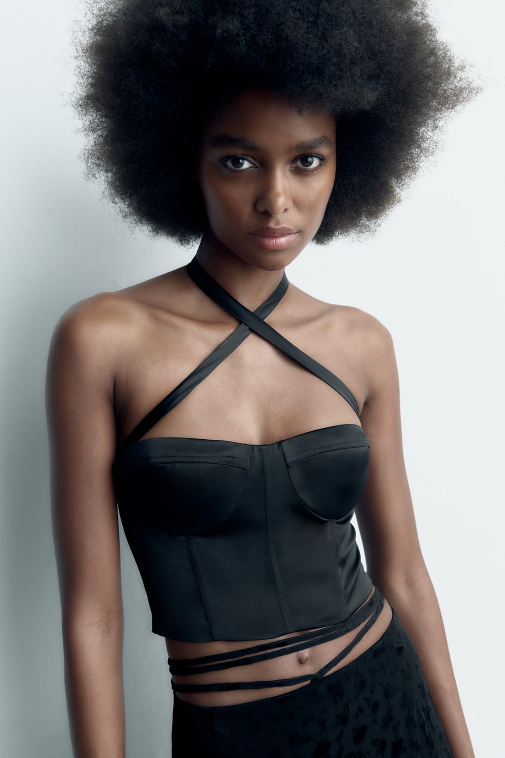 El negro también es para el verano. Un top de estilo corsé con efecto satinado que podrás llevar con tus vaqueros favoritos. Top corsetero de Zara (25,99 euros). 