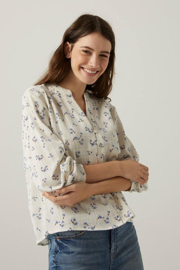 Blusa en tejido ligero con cuello mao, silueta fluida, manga larga, cierre de botones y estampado floral en azul y crudo. Está disponible a 14,99 euros, con descuento. Cómpralo aquí