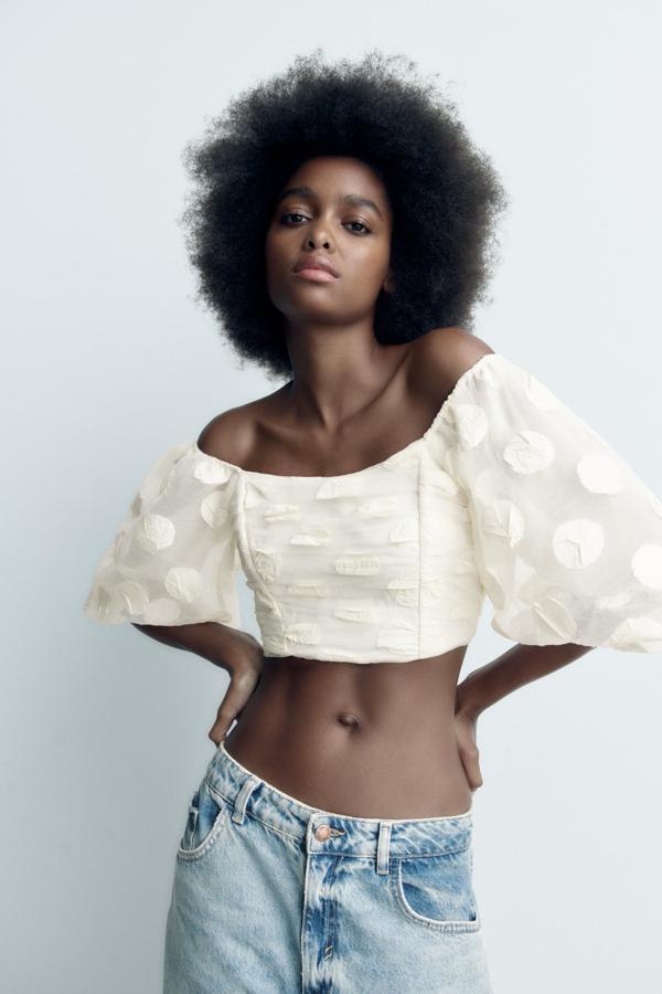 Cuerpo cropped de escote recto y manga corta abullonada. Destaca el detalle de elásticos tipo nido de abeja en la espalda. Tiene la zona de la espalda y de la barriga abierta, lo cual proporciona un frescor muy bueno para esta época del año. Es de Zara. Precio: 29,95 €.