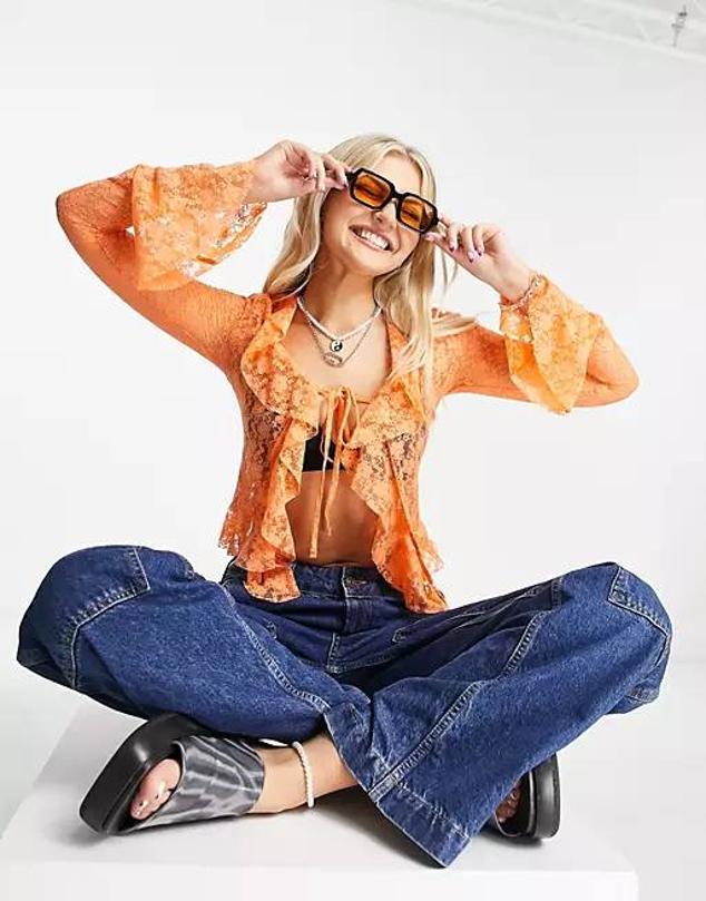 Blusa en tejido de encaje con manga larga, detalle de volantes en las terminaciones y cierre a través de lazada, color naranja, de Collusion. Está disponible en Asos a 34,95 euros.