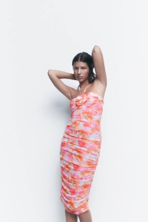 Vestido midi en tejido de tul fruncido con estampado floral, aros en el busto, silueta ajustada, cierre mediante lazada en el cuello y flor en el mismo tejido, en tonos rosa. Cuesta 25,95 euros.