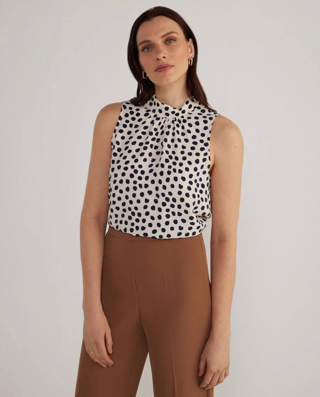 Blusa fluida con escote halter y detalle fruncido, en estampado de lunares blanco y negro, de Woman El Corte Inglés. La encontrarás con descuento por 23,99 euros.