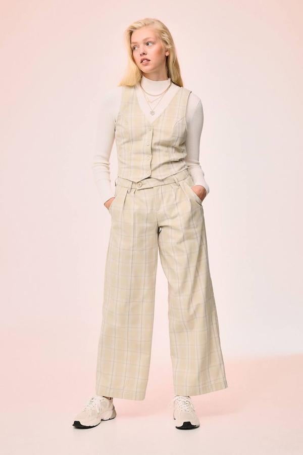 Traje beige claro con estampado a cuadros, conformado por chaleco con cierre de botones ajustado y pantalón con pinzas y pernera ancha, de H&M. Las prendas cuestan 14,99 euros y 19,99 euros.