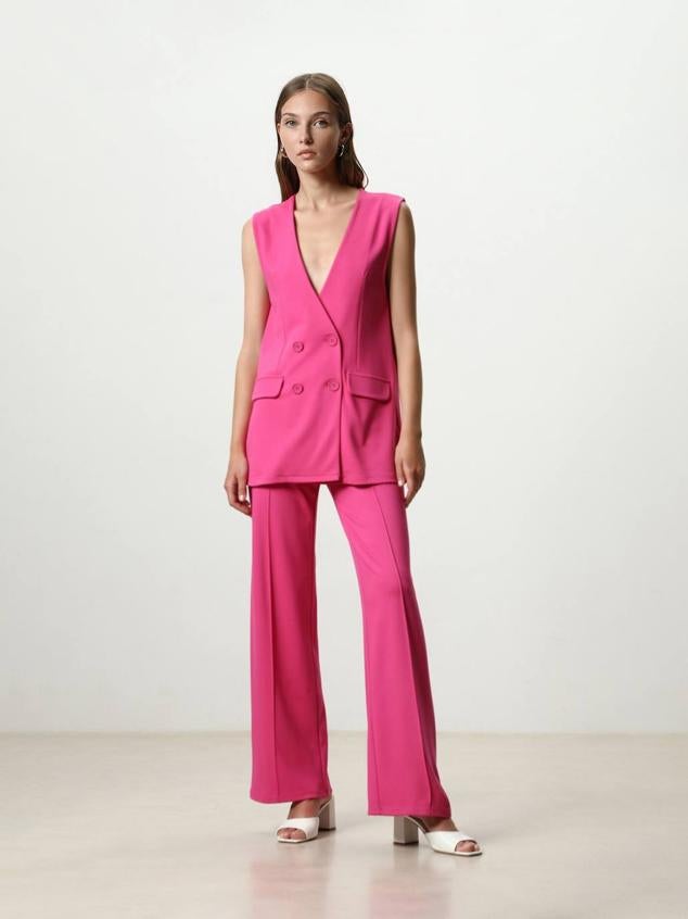 Traje de dos piezas con chaleco largo cruzado y pantalón largo fluido con nervio marcado, de Lefties. Puedes comprarlo en rosa o negro, por 19,99 euros, cada prenda.