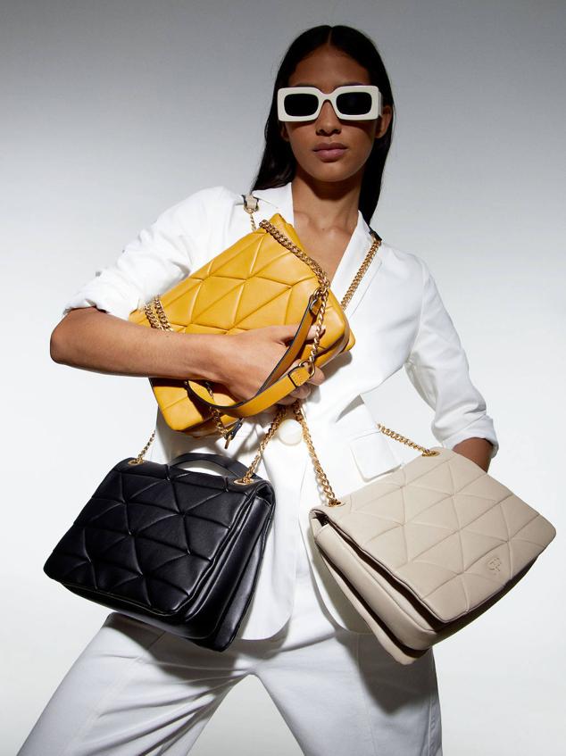 Bolso mediano acolchado con cierre de solapa por imán y doble asa de cadena con hombreras. Está disponible en negro, marrón y amarillo, con un coste de 29,99 euros.