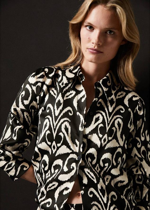 Camisa en tejido fluido y satinado con manga larga, cuello solapa, cierre de botones y estampado bicolor en negro y blanco, de Mango. Tiene un coste de 29,99 euros.
