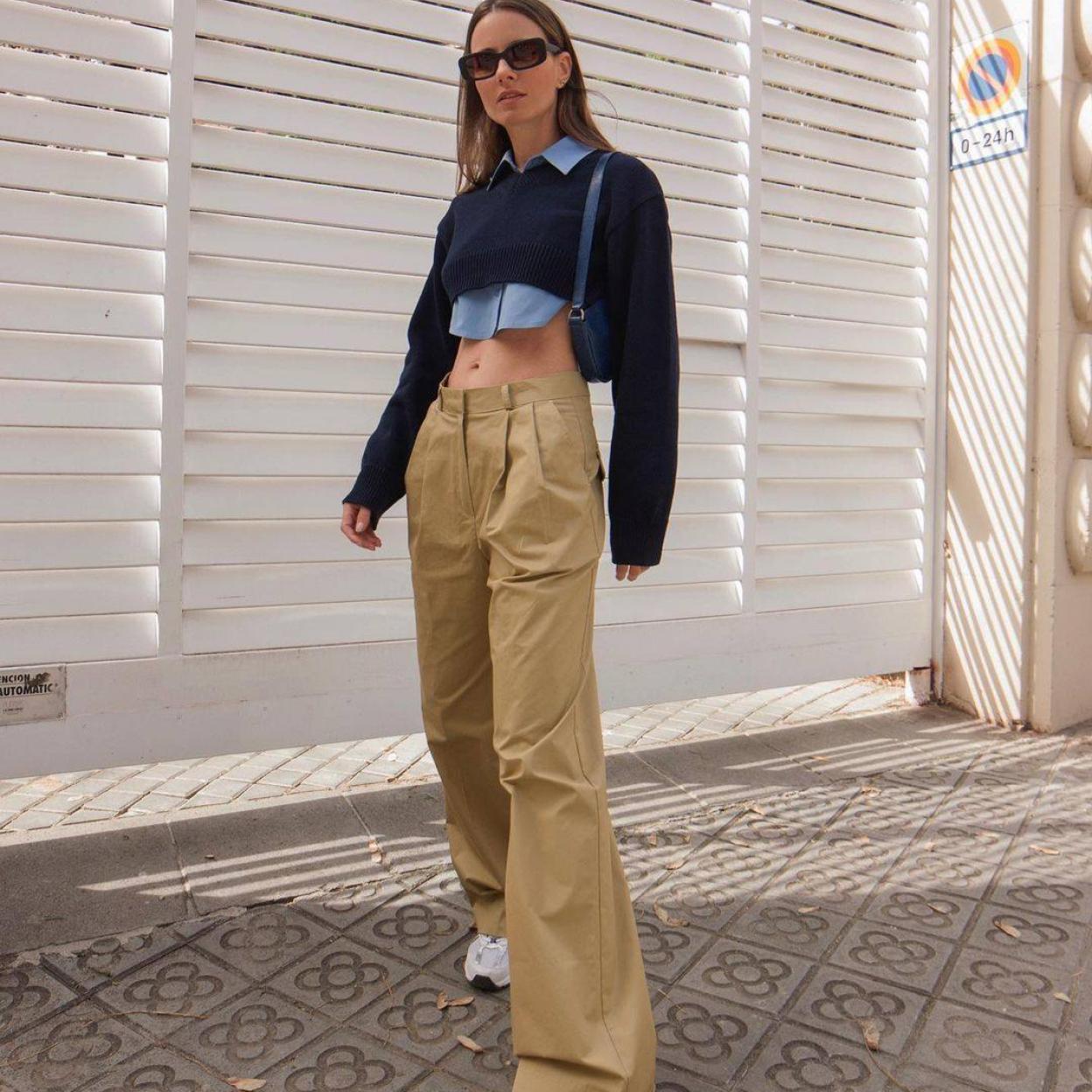 La influencer lleva un work look modernizado con camisa, jersey y pantalón de vestir.