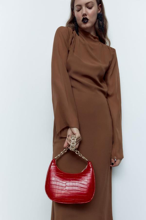 Una nota de color, en un tono otoñal, para los días de entretiempo.Bolso de asa corta con cadena dorada de Zara 