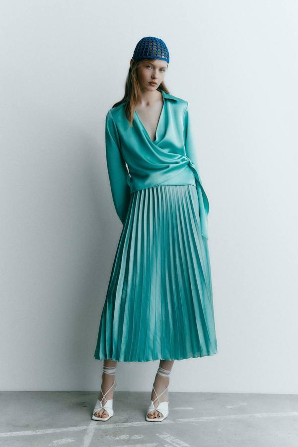 Falda midi en tejido plisado con acabado satinado, tiro alto y diseño evasé, color turquesa claro, de Zara. Está disponible por 25,95 euros.