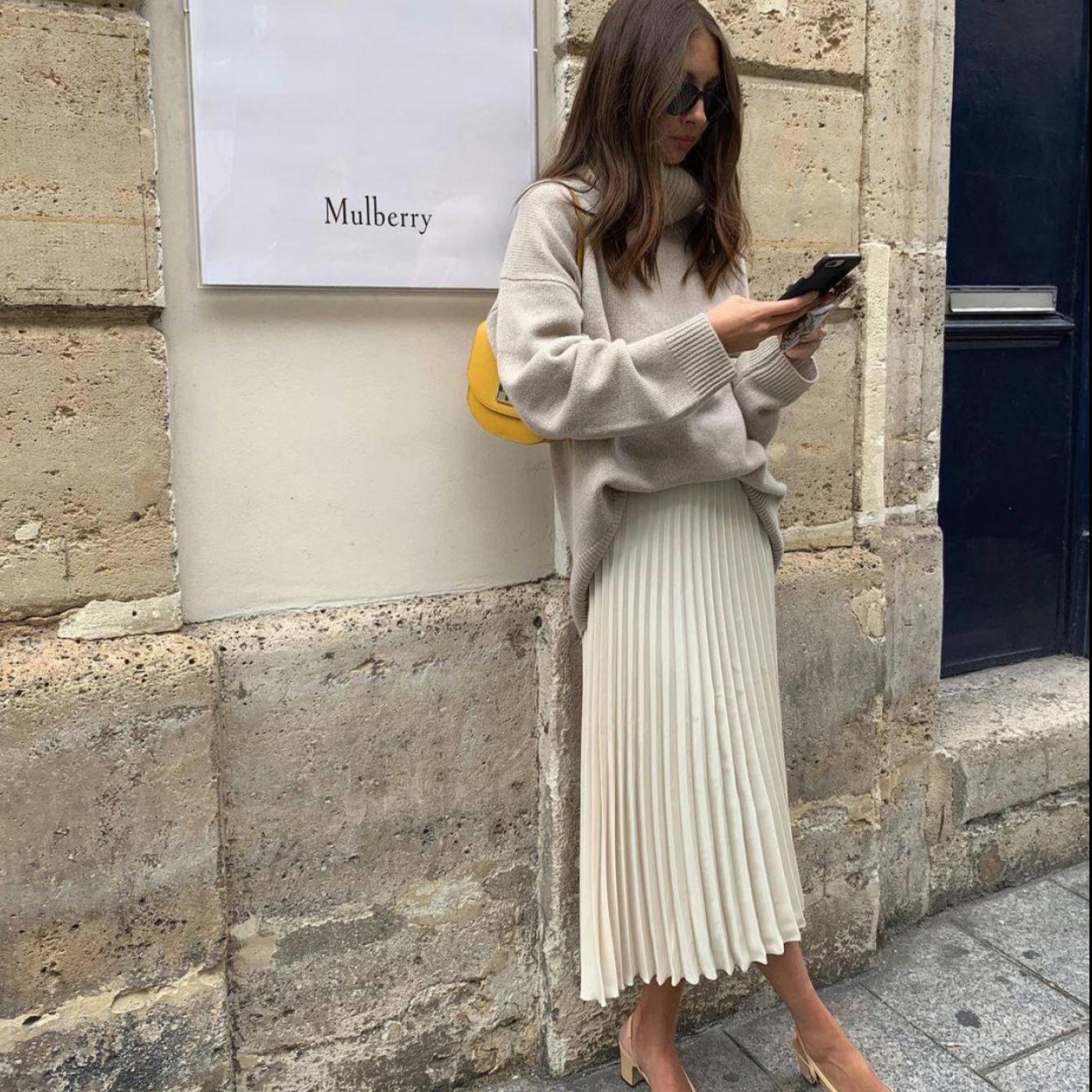La influencers conjunta un total look neutro con falda midi plisada en color crema