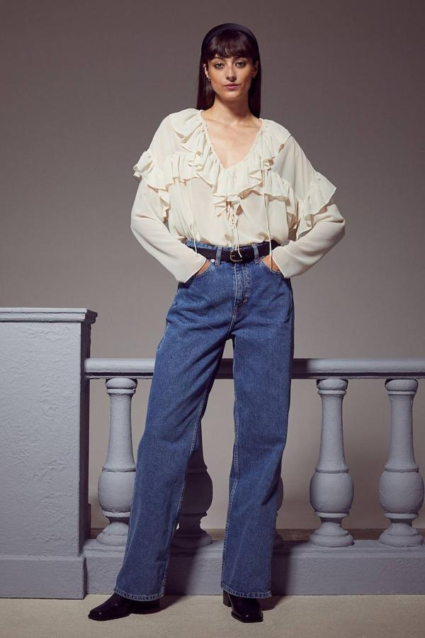 Blusa en tejido de gasa vaporosa con silueta relajada, escote de pico con lazada, manga larga y detalles de volantes, tono crema, de H&M. Cuesta 24,99 euros.