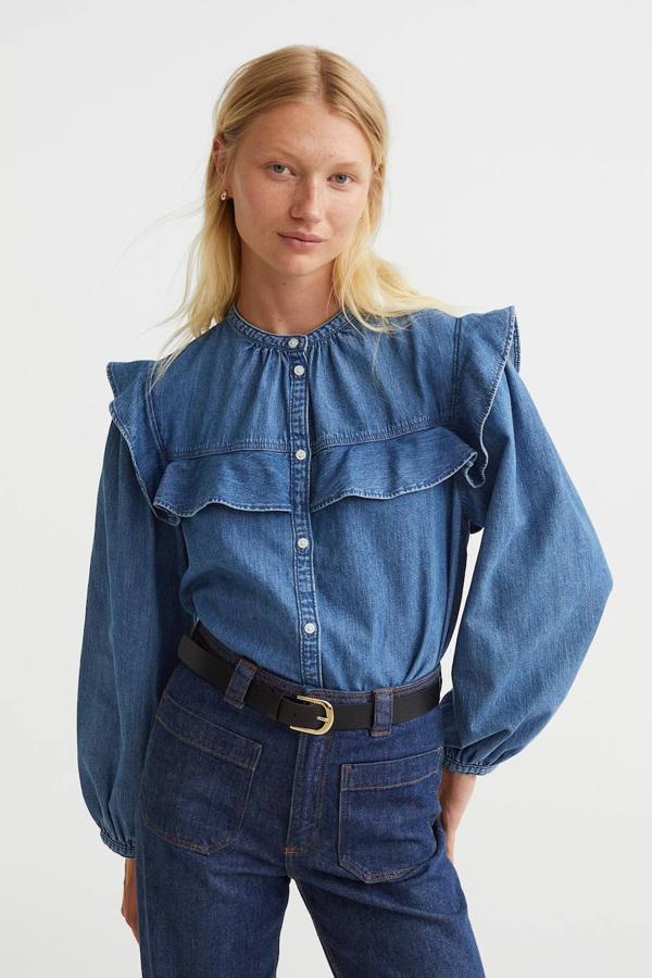 Blusa en tejido denim con cuello redondo, manga larga abullonada, cierre de botones delantero y volantes, en azul, de H&M. La encontrarás por 39,99 euros.